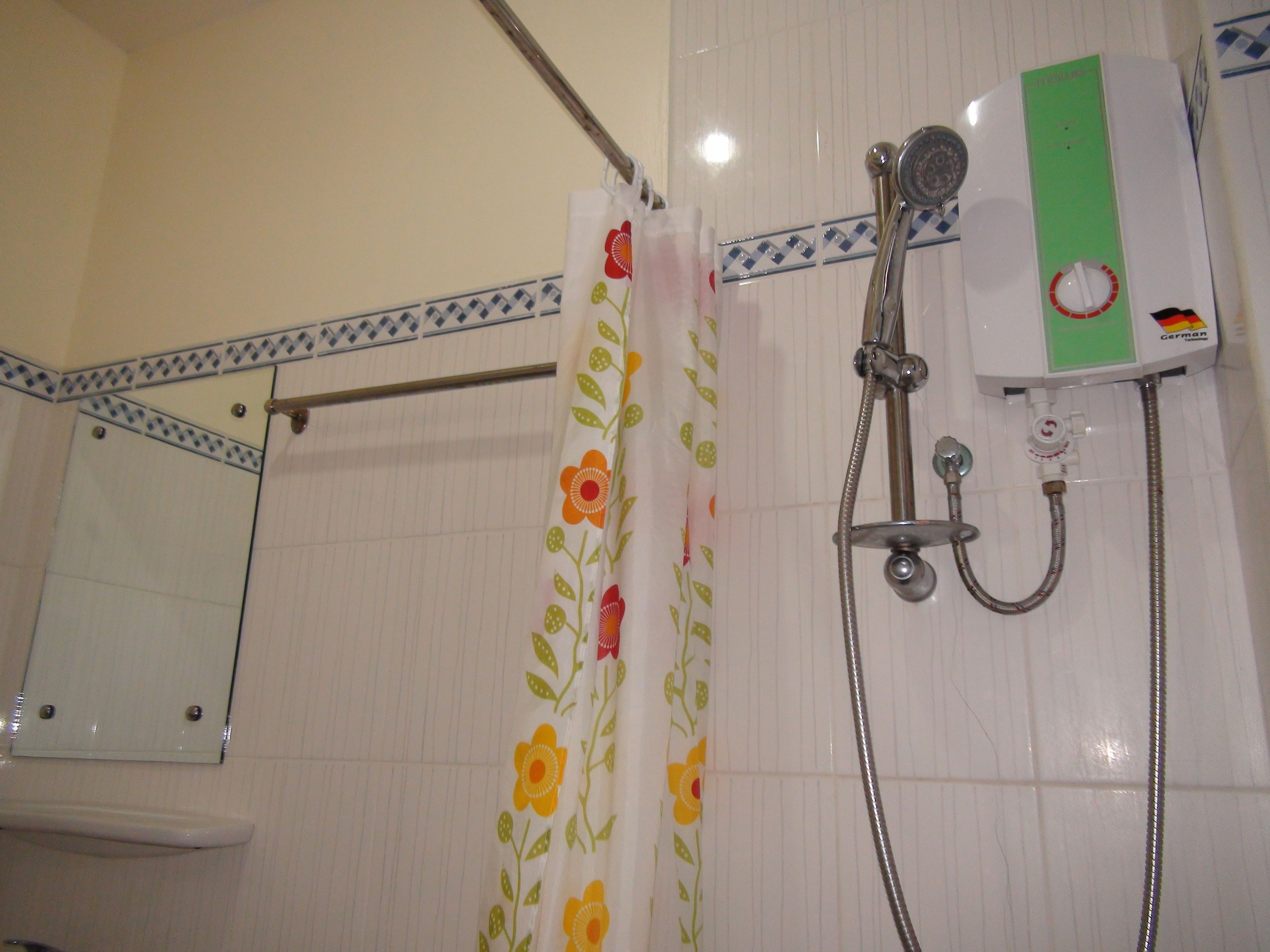 Une salle de bain avec une douche, un porte-serviettes et un miroir.