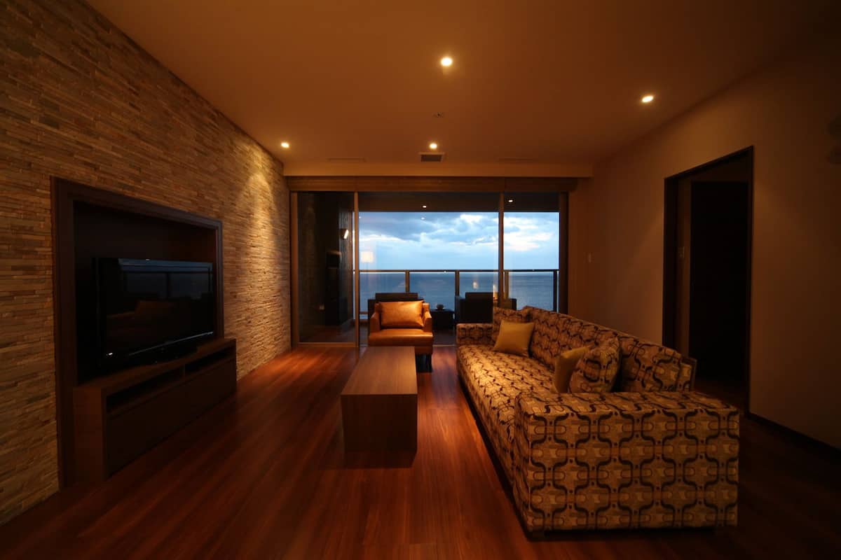 Uma sala de estar moderna com uma grande televisão de tela plana, um sofá estampado e uma mesa de centro de madeira.