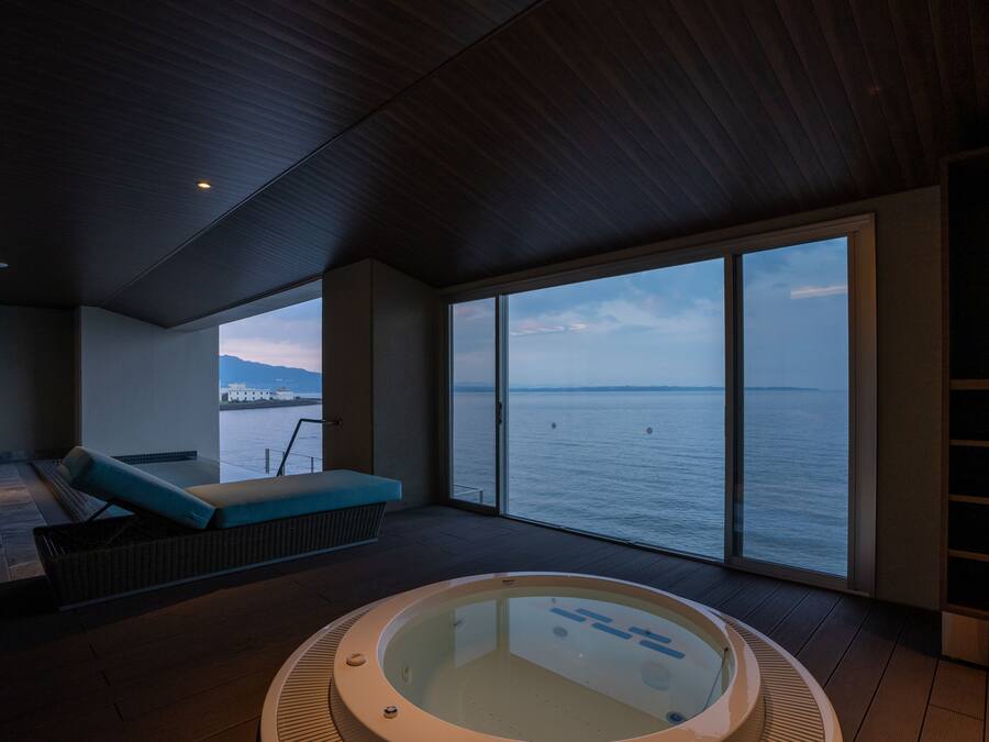Una habitación moderna con un ventanal grande, un jacuzzi y una zona de estar con vista al mar.