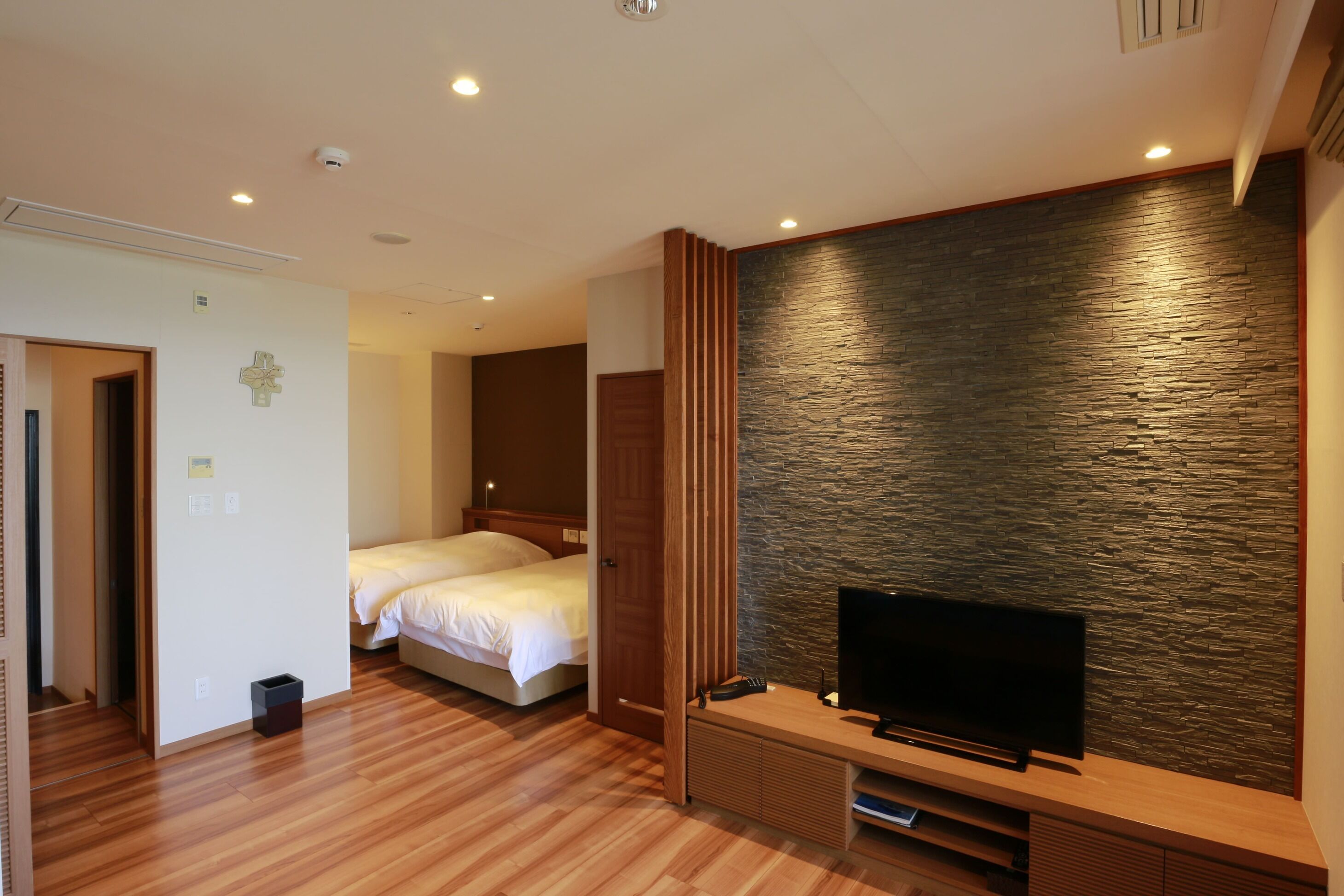 Een hotelkamer met een bed, een televisie en een muur met een stenen textuur.