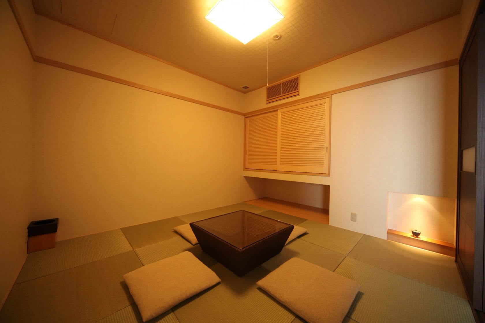 A traditional Japanese tatami room with a low table, cushions, and a sliding door.