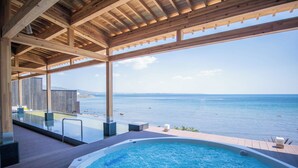 A wooden deck with a pool and a view of the sea.