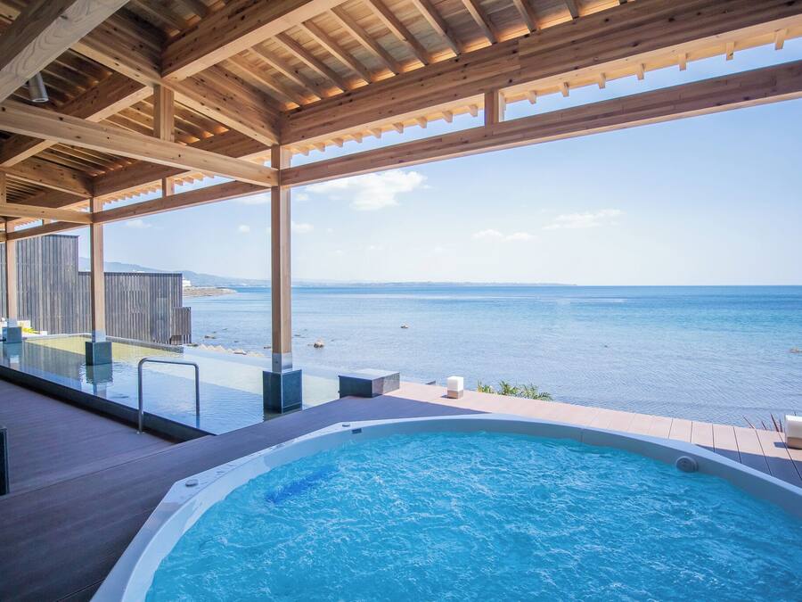 A wooden deck with a pool and a view of the sea.