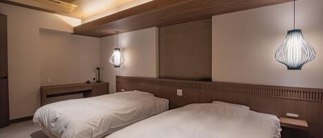 Une chambre d’hôtel avec deux lits, des têtes de lit en bois, une table de chevet avec une lampe et un grand miroir au mur.