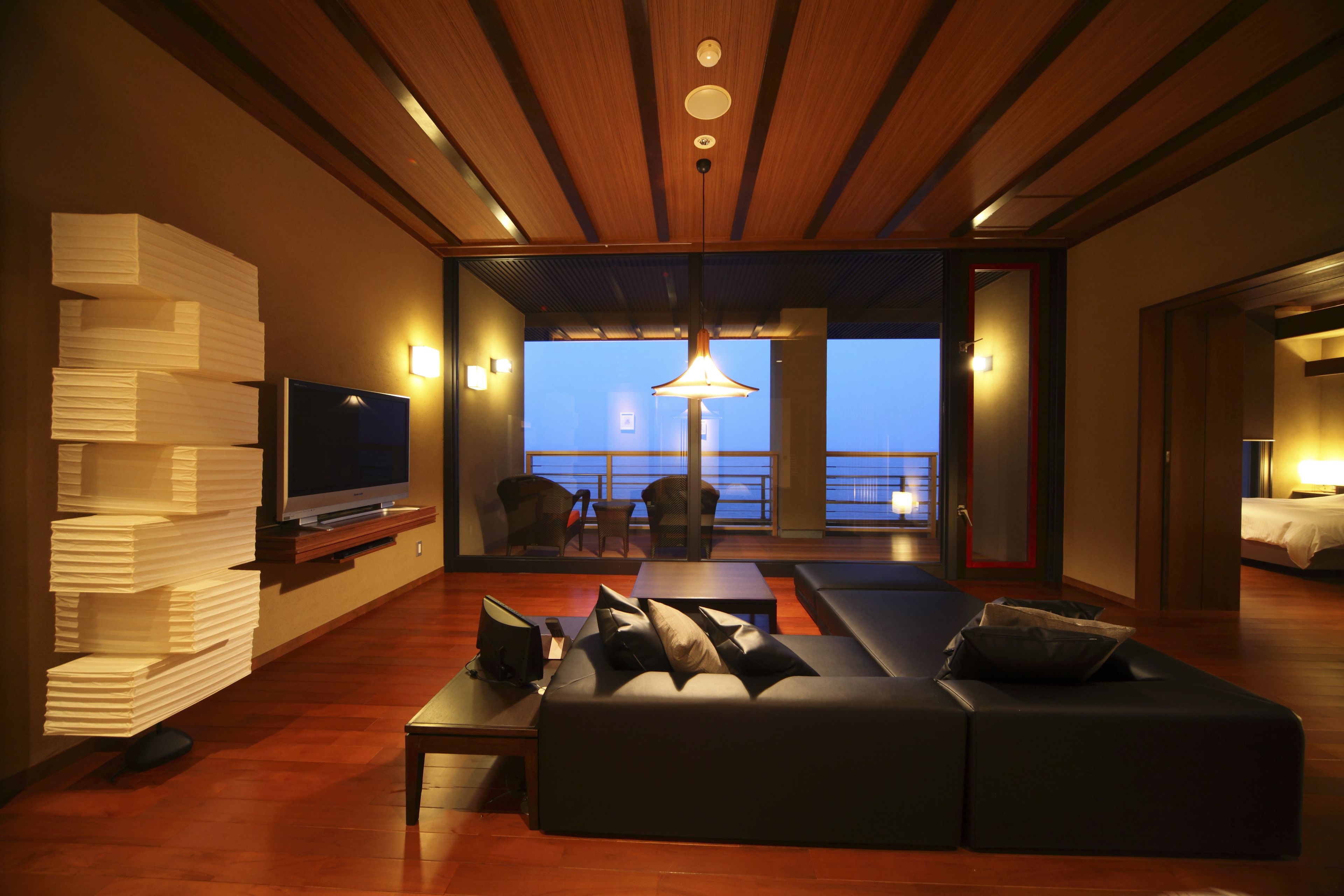 A modern living room with a large sectional sofa, a flat-screen TV, and a dining area with a table and chairs.