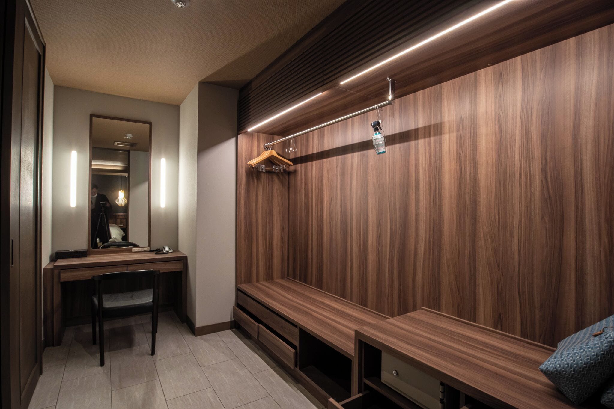 A modern bathroom with a wooden vanity, a mirror, and a bench.