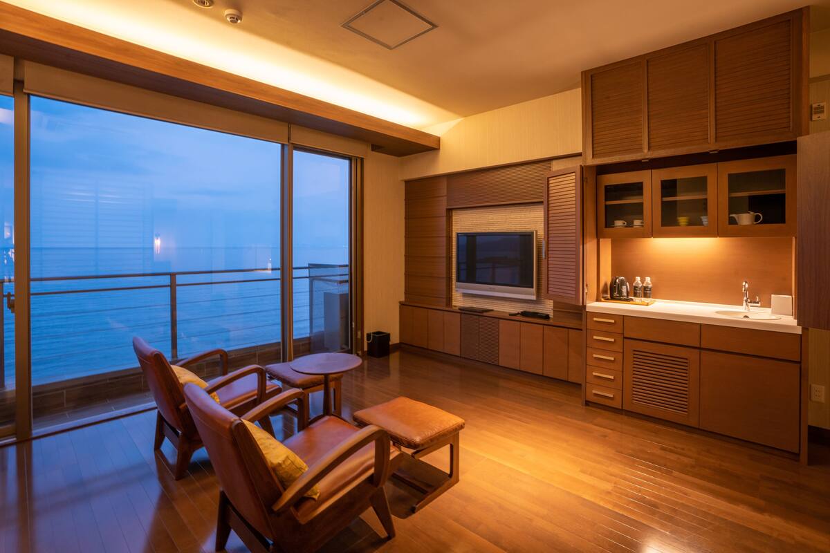Eine moderne Küche mit Holzausstattung, einem großen Fenster und einem Balkon mit Meerblick.