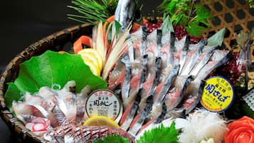 A variety of fresh seafood including fish, shrimp, and squid, arranged in a basket with decorative elements like leaves and flowers.