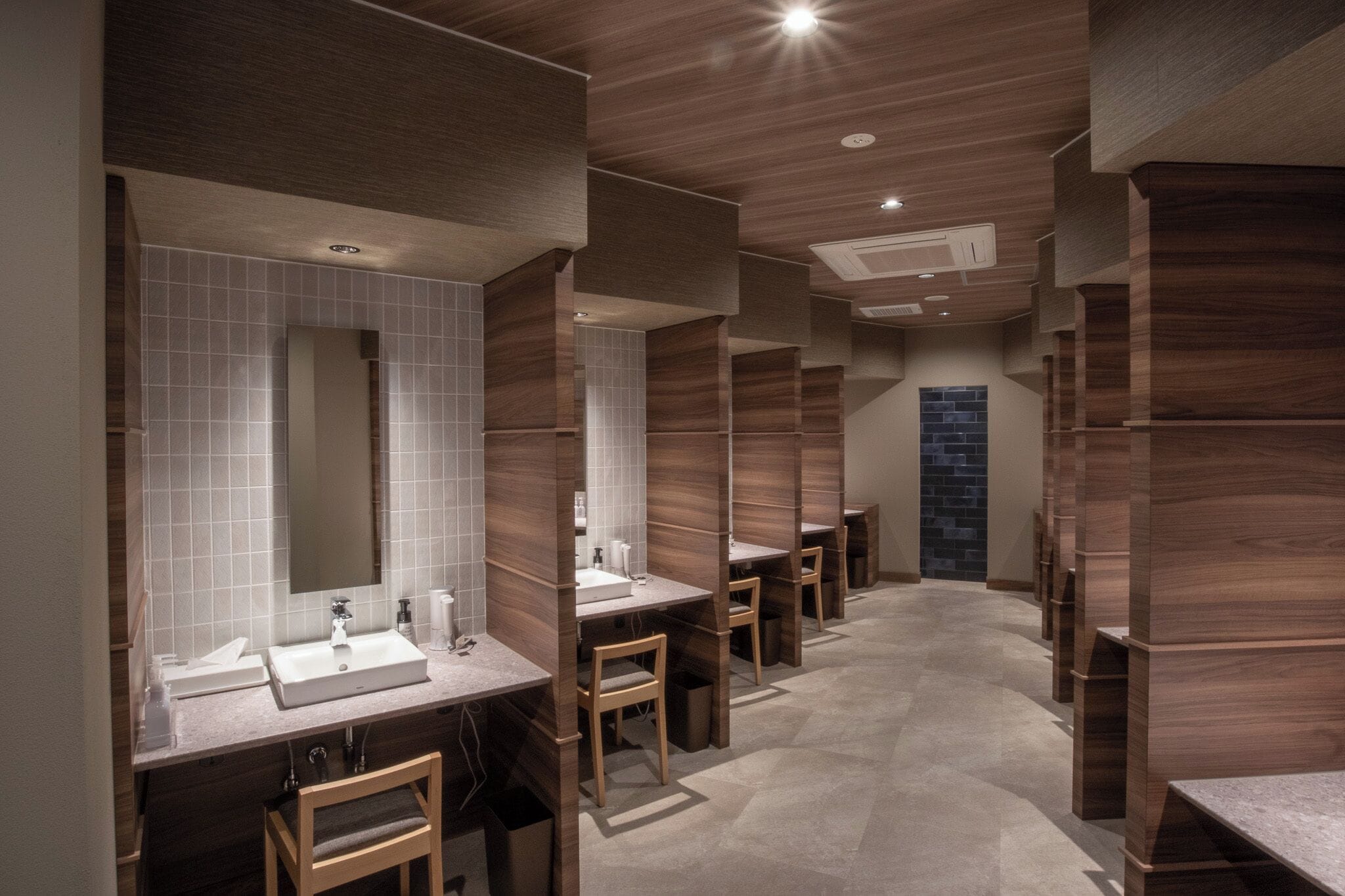 A modern bathroom with multiple sinks, wooden paneling, and a tiled floor.