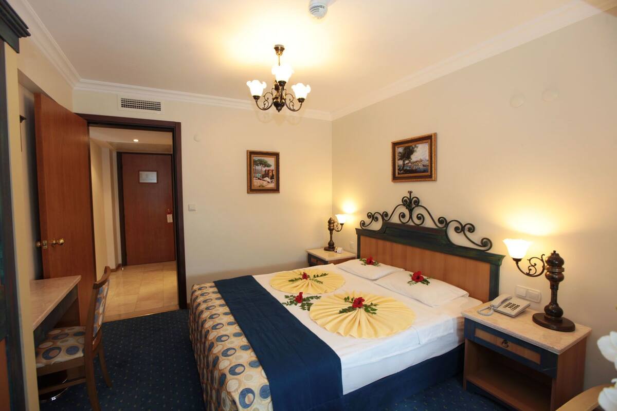 A hotel room with a bed, bedside tables, a desk, and a chair.