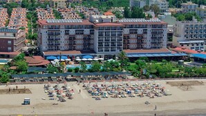 Un hôtel situé en bord de mer, avec plusieurs étages, des espaces de détente en plein air et un espace piscine.