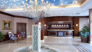 Un hall d’entrée agrémenté d’un lustre, d’un comptoir de réception et d’une fontaine.