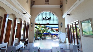 Un hall d’entrée spacieux avec un haut plafond en bois, des portes en arc de cercle et une grande fenêtre donnant sur l’extérieur.