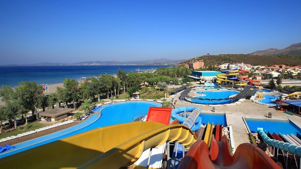 Un parc aquatique doté de nombreux toboggans et de plusieurs piscines, entouré d’immeubles et bordé d’une plage.