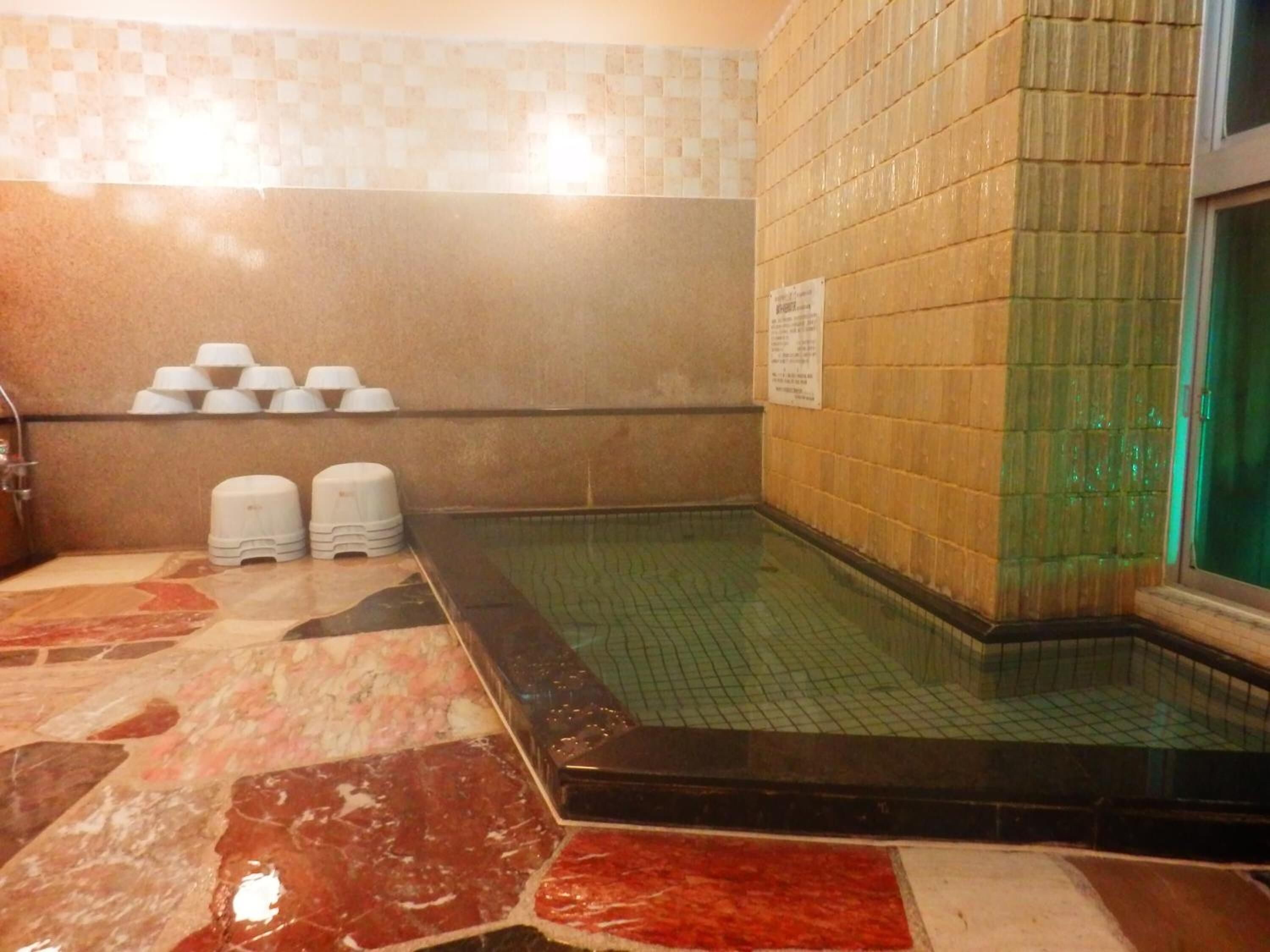 A tiled bathroom with a small pool, a tiled wall, and a sign on the wall.