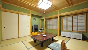 A tatami mat room with a low table, sliding doors, a television, and a traditional window with shoji screens. - Nakayasu Ryokan (Kanazawa)