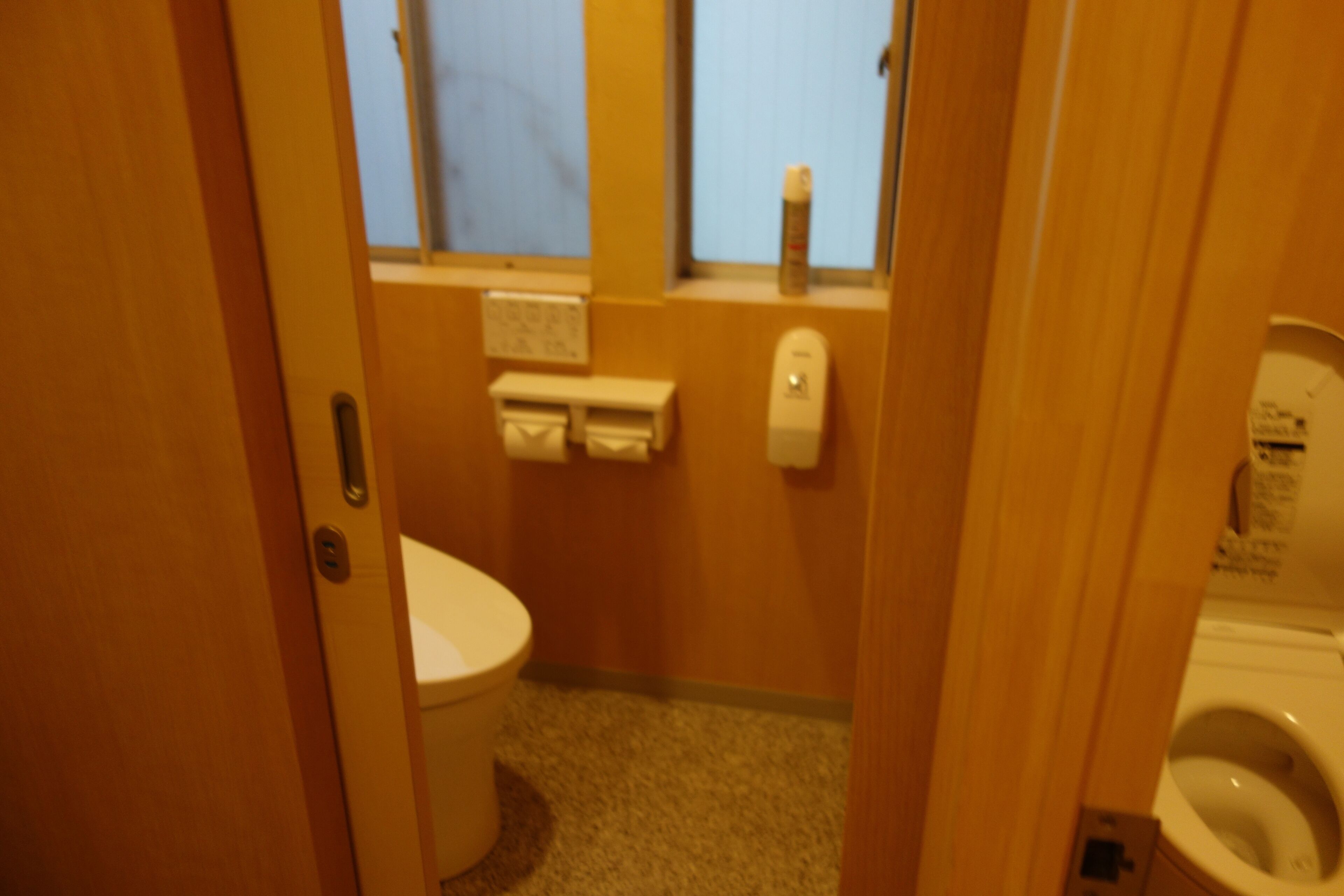 A small bathroom with a toilet, a sink, and a window.