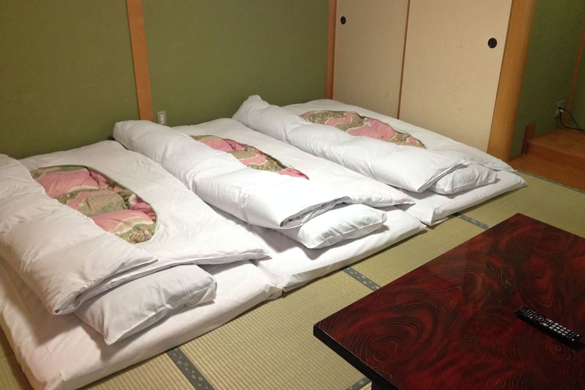 A room with two beds, a wooden table, and a remote control.