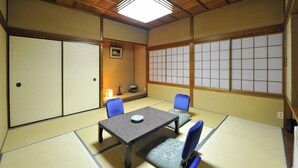 A traditional Japanese room with tatami flooring, a low table, and blue chairs. - Nakayasu Ryokan (Kanazawa)