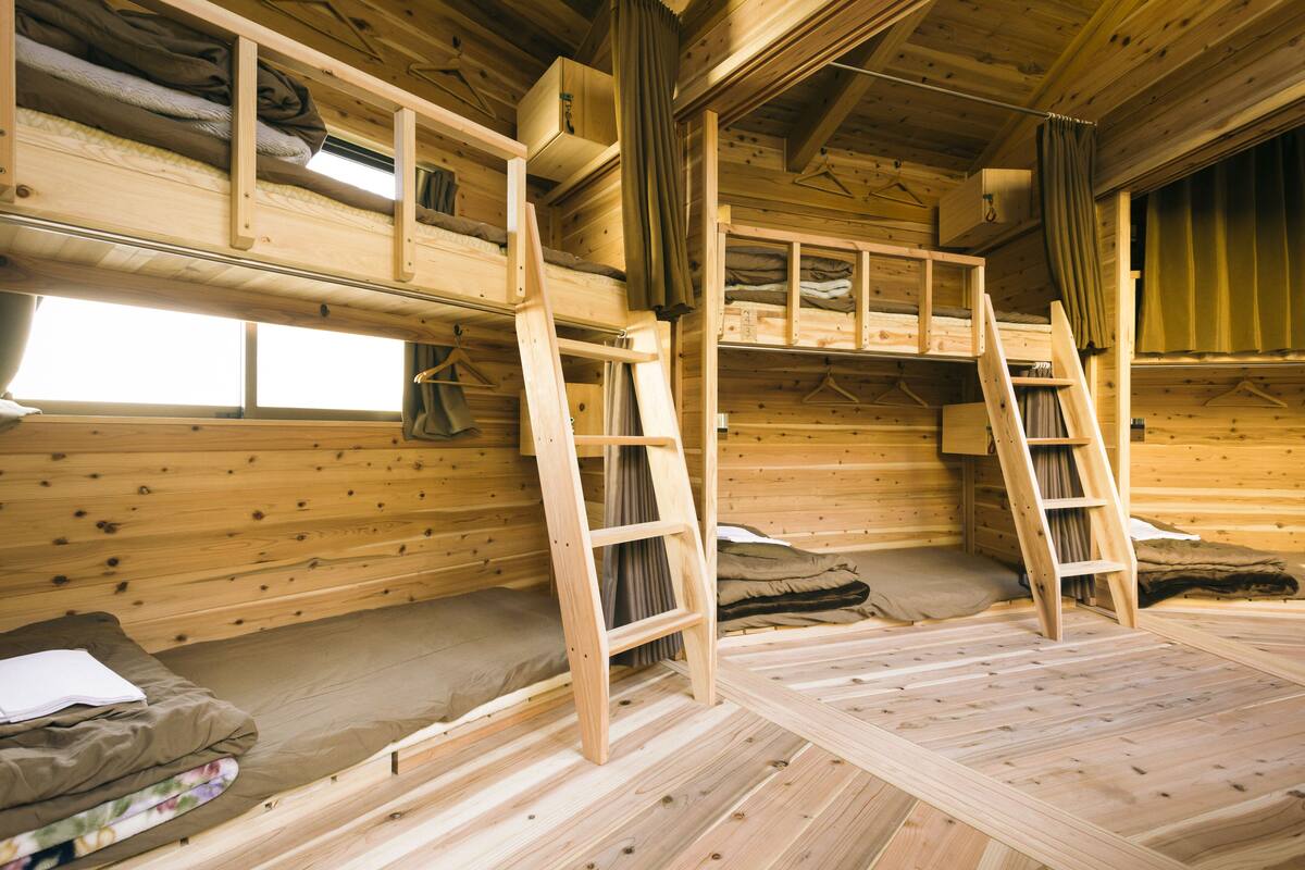 A cabin with bunk beds, wooden floors, and a ladder.