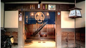 A traditional Japanese entrance with a wooden door, a lantern, and a sign indicating a public toilet. - Oyado Chogoro (Takayama)