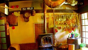 A traditional Japanese room with tatami mats, a shoji screen, a wood stove, and a hanging shimenawa. - Oyado Chogoro (Takayama)