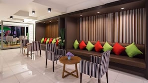 Um hall moderno com cadeiras listradas, uma mesa redonda e um sofá com almofadas coloridas.