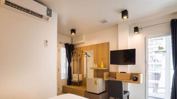 Quarto de hotel moderno com cama, escrivaninha, televisão e vista da cidade pela janela.