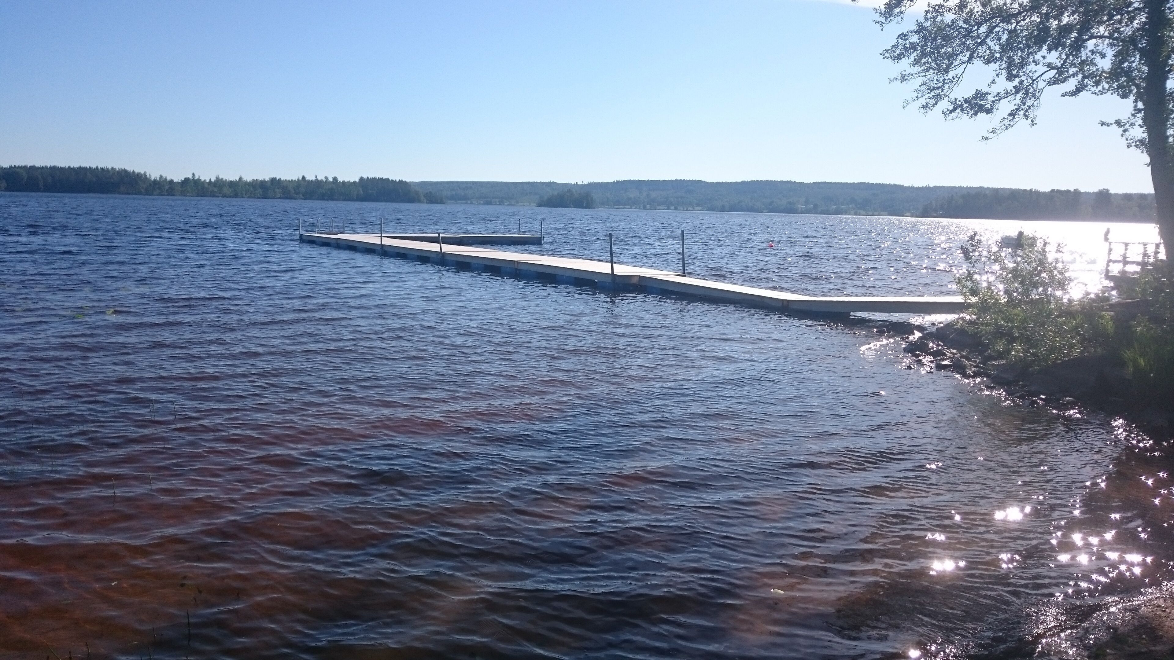 En stilla sjö med en träbrygga som sträcker sig ut i vattnet.
