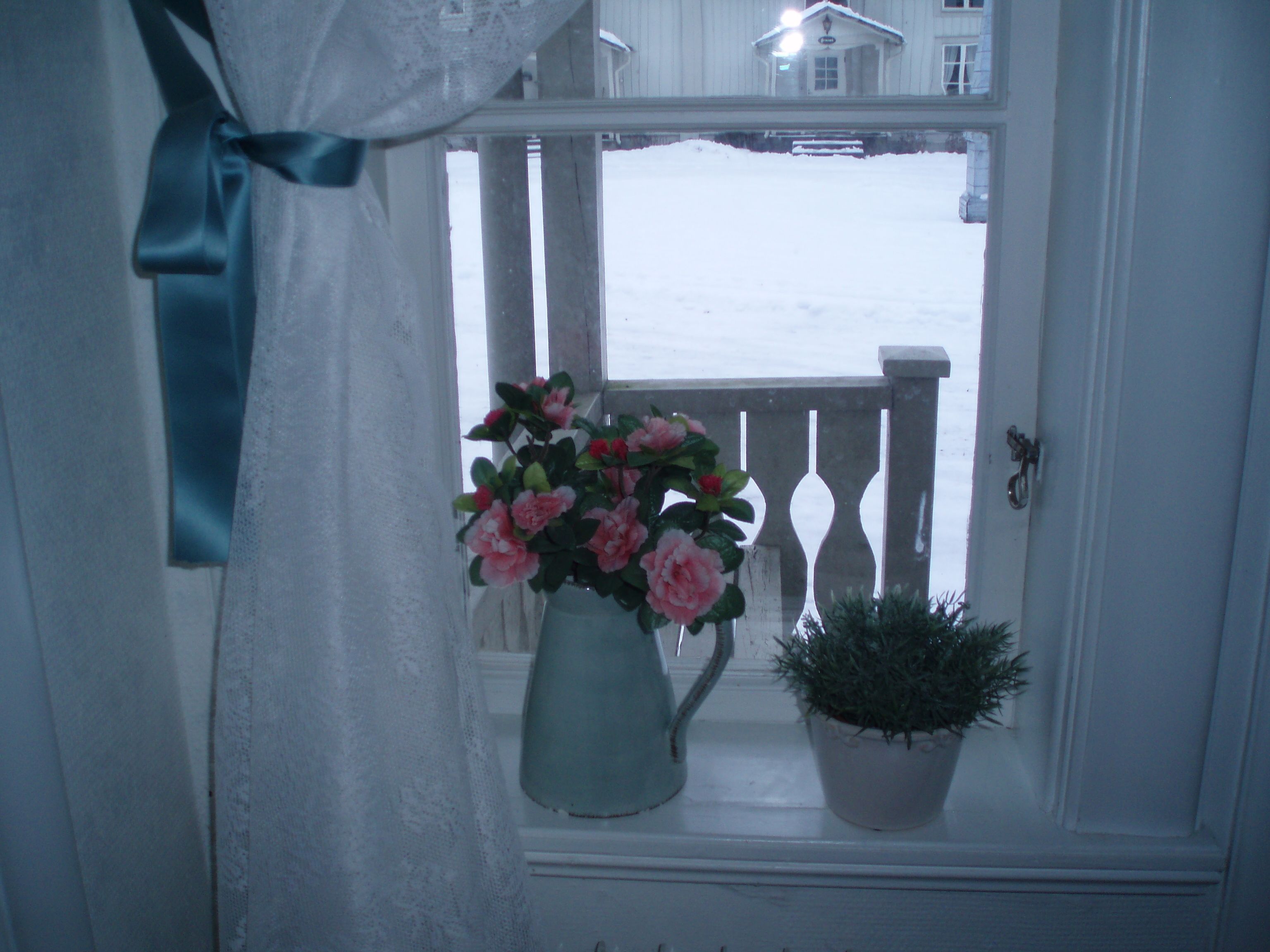 A window with a curtain tied back, revealing a snowy view outside.