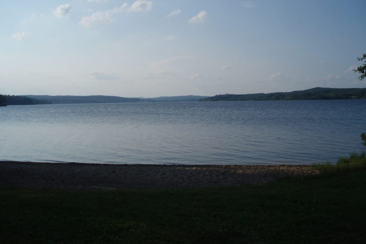 Un lago tranquilo con cielo despejado y colinas lejanas.