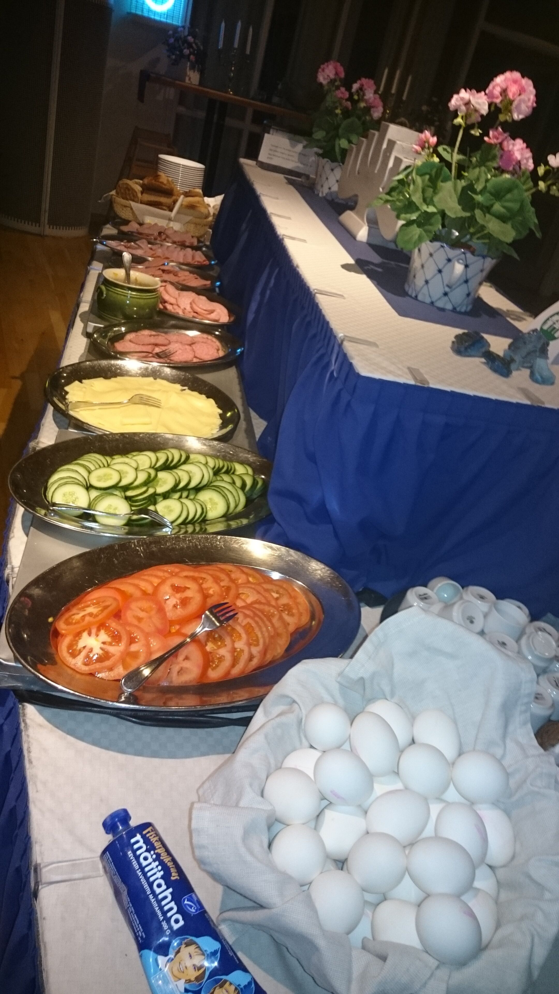 Una mesa de buffet con diversas opciones de comida, incluyendo pepinos en rodajas, tomates y huevos.
