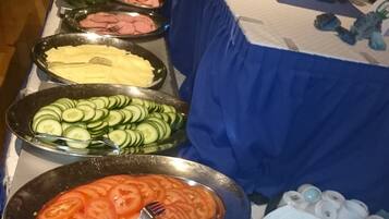 Una mesa de buffet con diversas opciones de comida, incluyendo pepinos en rodajas, tomates y huevos.