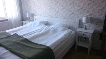 A bedroom with a bed, nightstands, and a window.