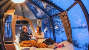 Une pi èce circulaire et chaleureuse, avec un lit et une fenêtre donnant sur un paysage enneigé.