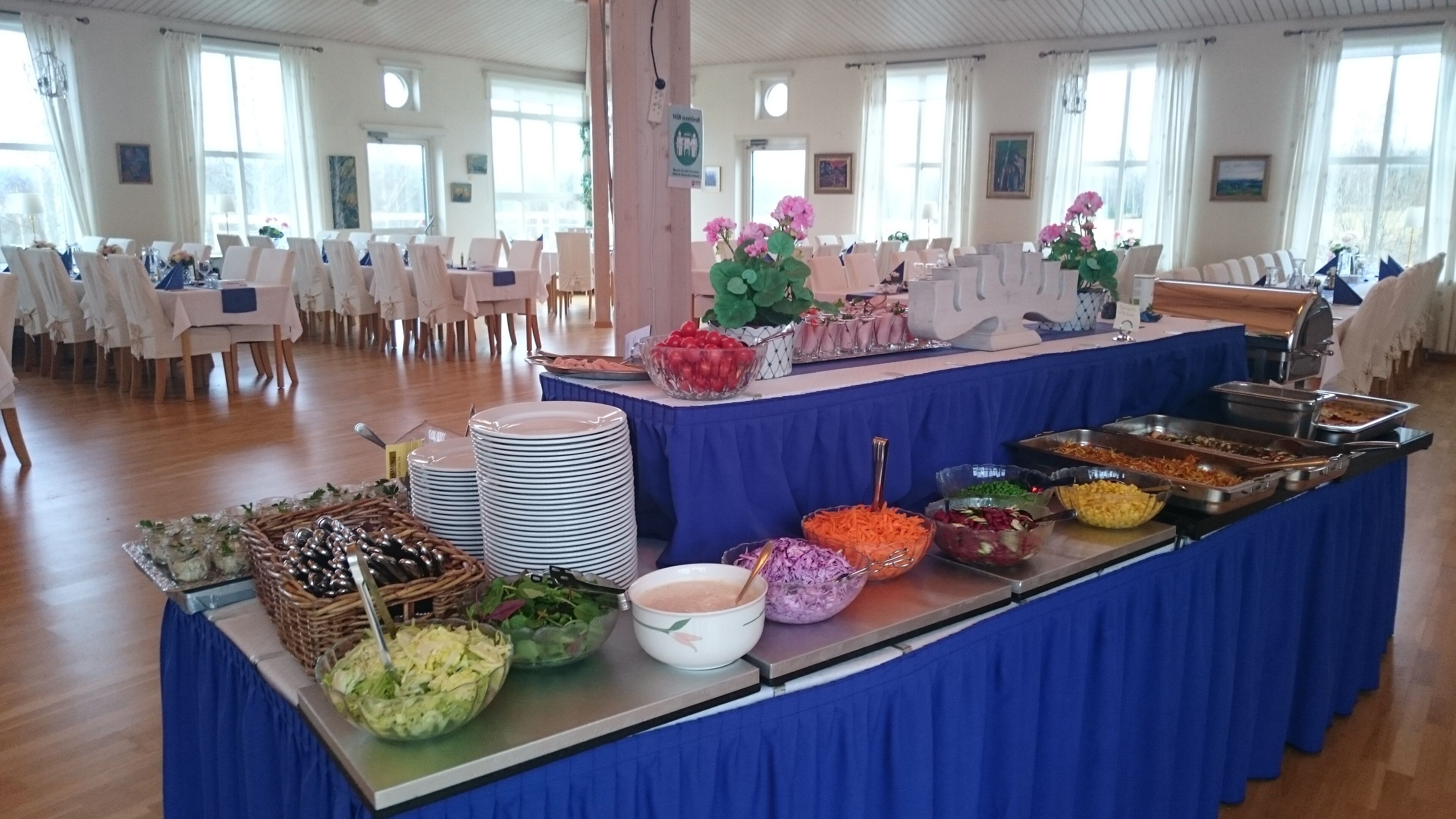 A buffet setup with various food items and a blue tablecloth.