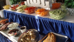 Une table de buffet garnie de divers plats et d’un grand morceau de saumon.