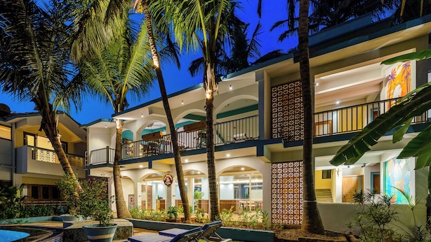 A hotel with a pool area, lounge chairs, and palm trees. - Hotel Lua Nova (Baga)