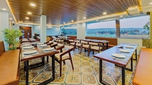 A restaurant with wooden ceiling, large windows, and a view of the landscape. Tables are set with plates and cutlery. - Hotel Lua Nova (Baga)