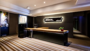 A modern reception area with a reception desk, a digital display, and a welcome sign. - StayInn Taipei (Taipei)