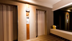 A hotel hallway with striped walls, a wooden accent wall, a clock, and a small yellow teddy bear on a bench. - StayInn Taipei (Taipei)