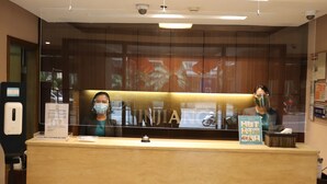 A reception desk with a glass partition, a digital screen, and a sign about health and safety. - Jinjiang Inn Ortigas (Pasig)