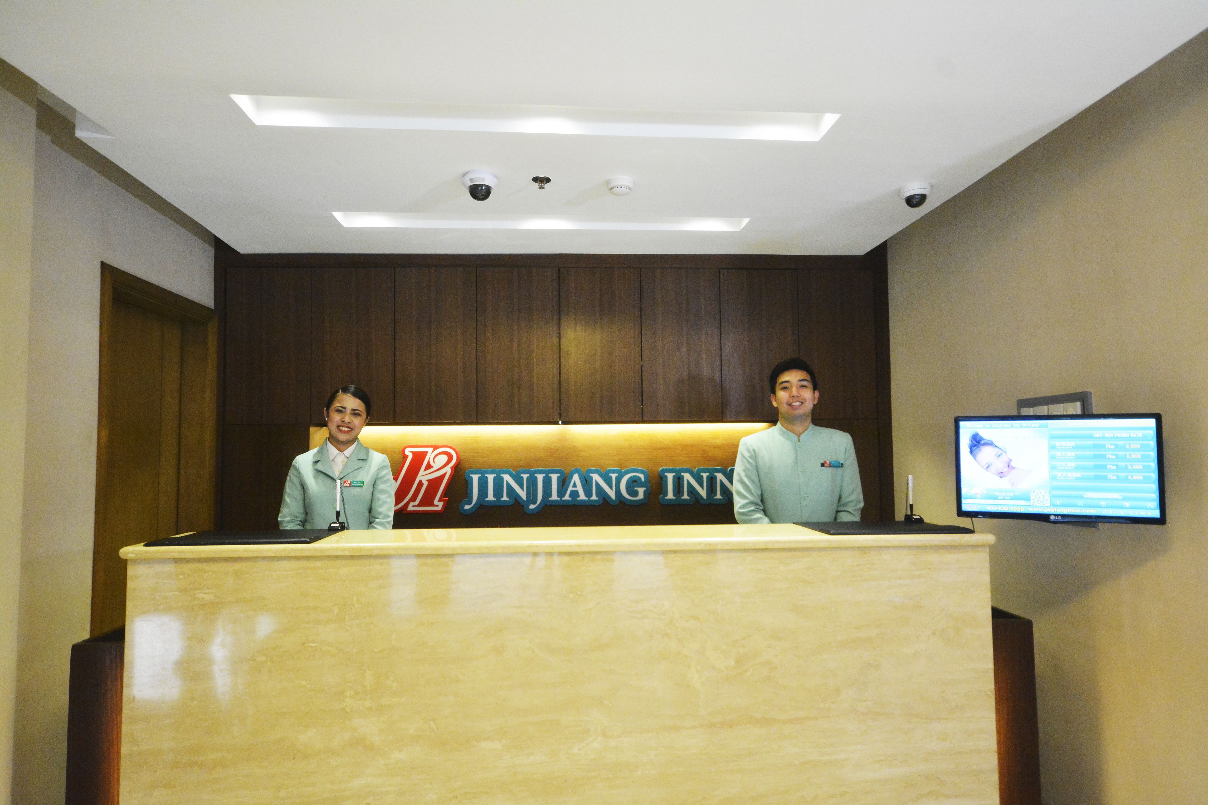 A reception desk at Jinjang Inn with a digital screen displaying information.