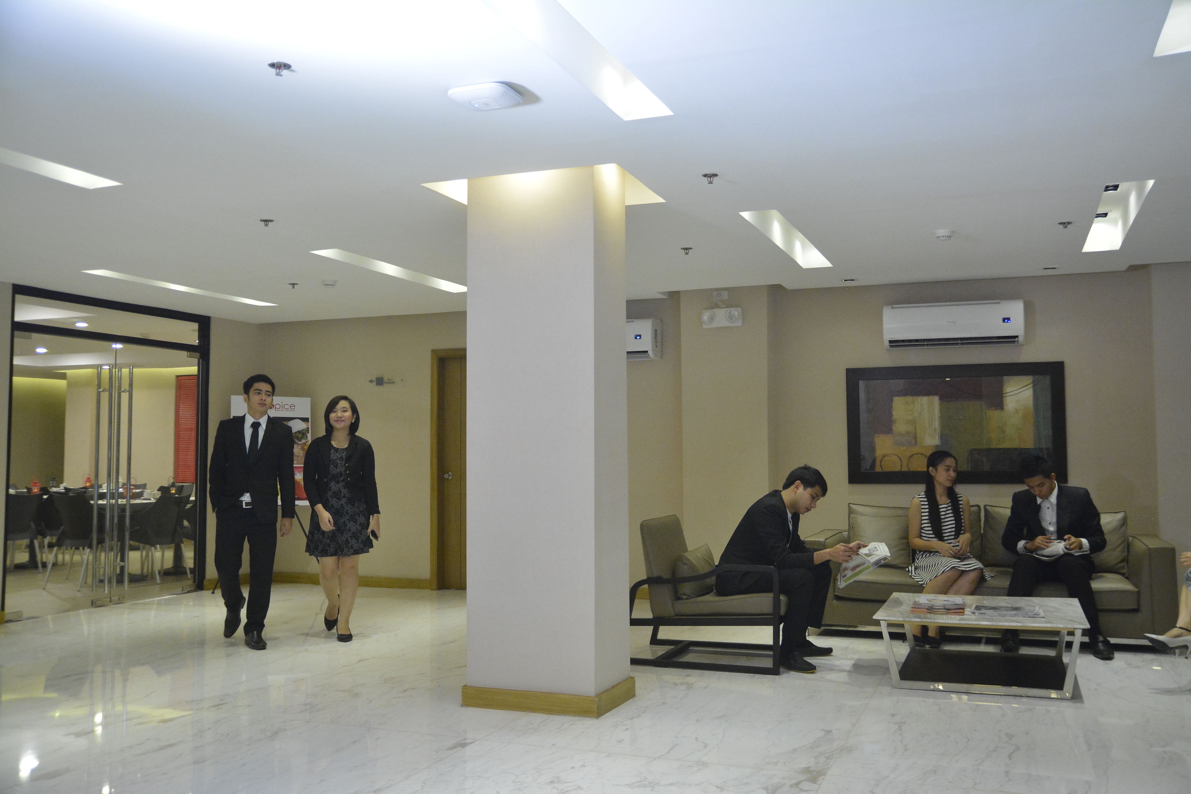 A modern lobby with a glass door entrance, a reception area, and a seating area with a coffee table.