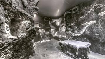Interno di una grotta innevata, con formazioni rocciose e una panchina.