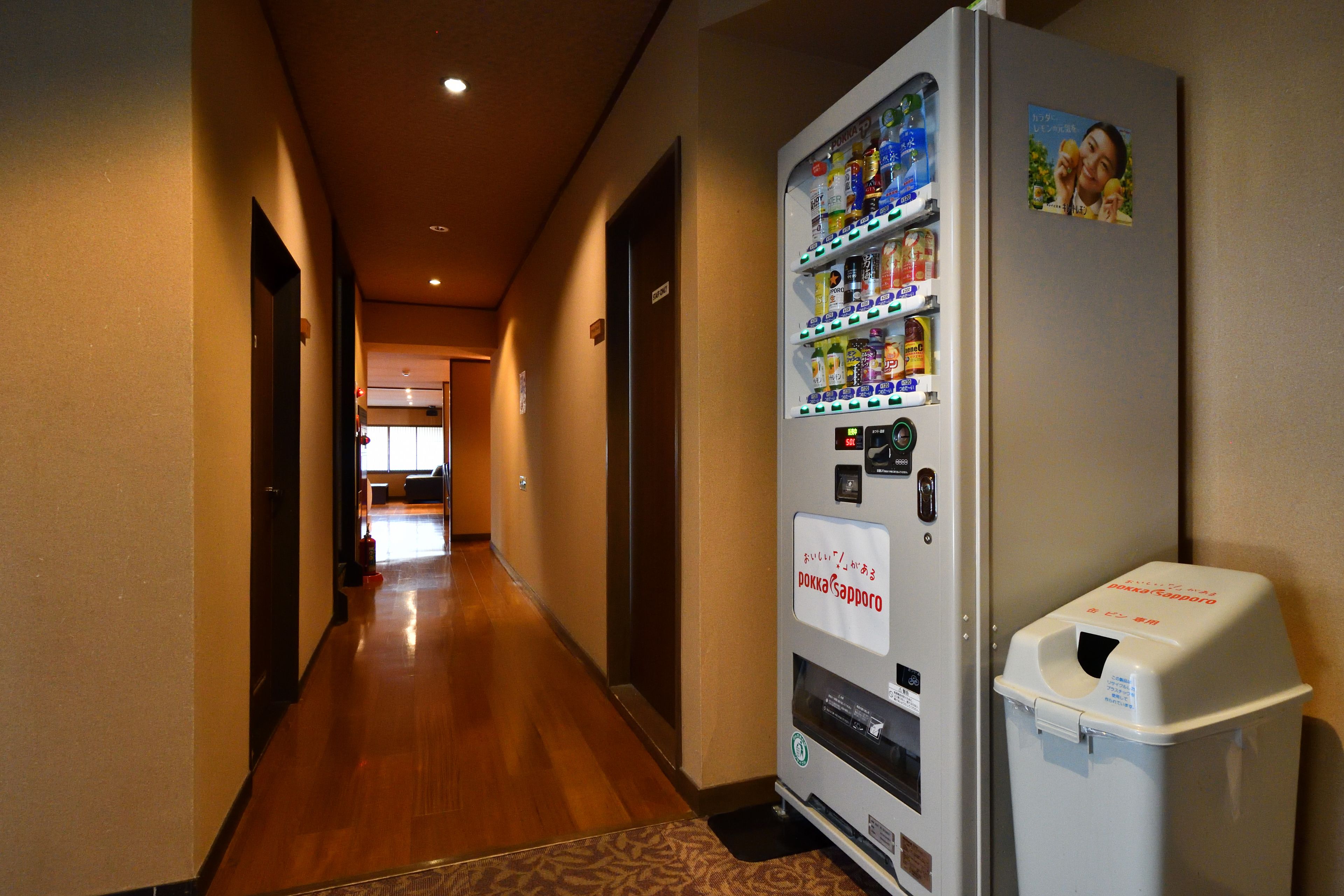 Um corredor de hotel com uma máquina de venda automática repleta de lanches e bebidas.