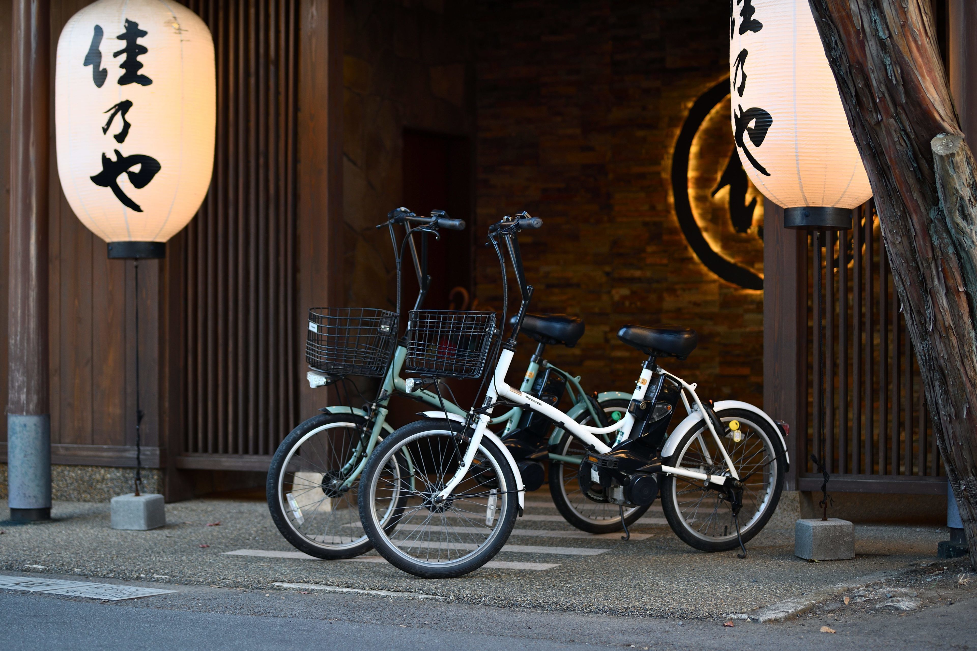 Deux vélos sont garés devant un bâtiment orné de lanternes japonaises traditionnelles.