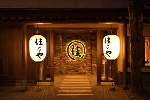 A traditional Japanese entrance with wooden doors and a stone wall. - Kusatsu Onsen Ryokan Yoshinoya (Kusatsu)