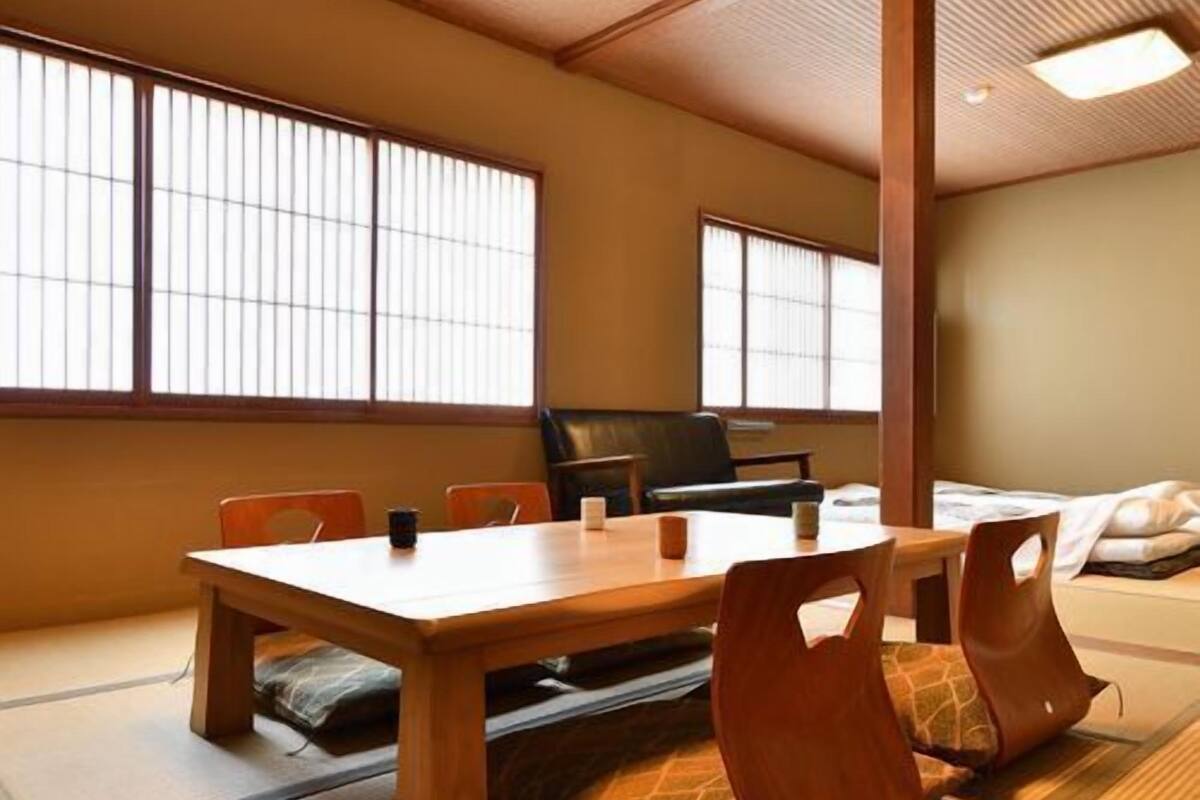 A traditional tatami mat room with a wooden table, chairs, and a futon bed.