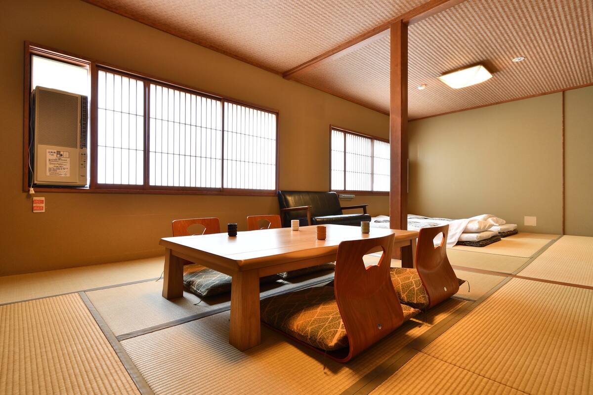 A traditional Japanese room with tatami flooring, a low table, and sliding doors.